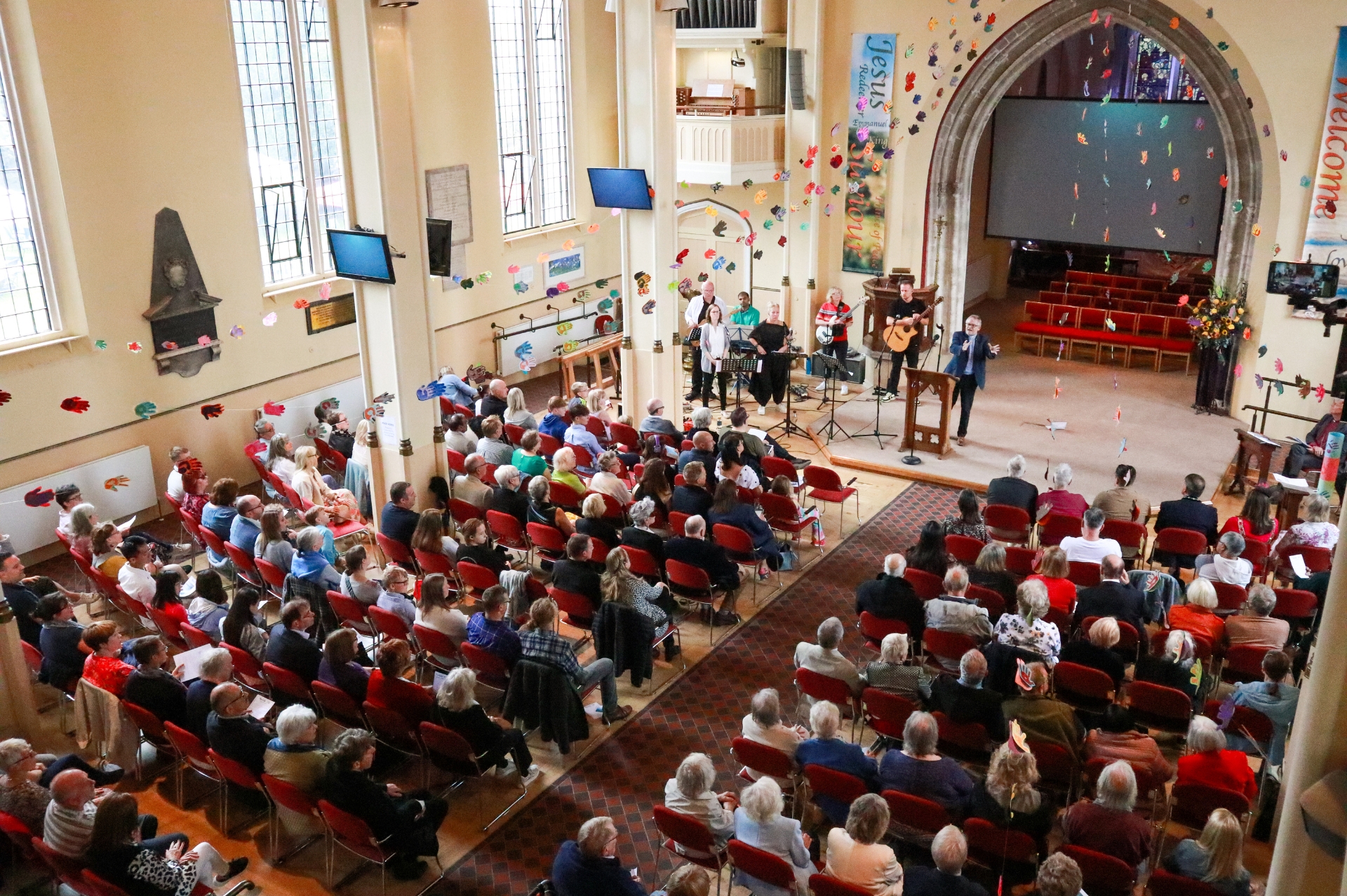 Interior shot of St Peter's Church in Cherstey with congregration, decorated with colourful crafted flowers