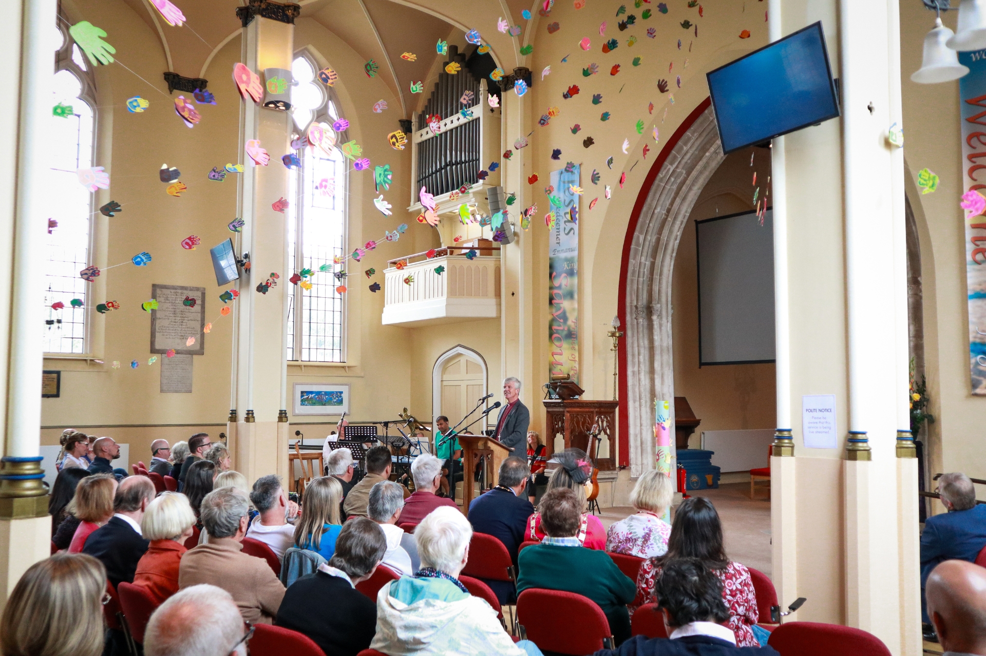 Interior shot of St Peter's Church in Cherstey with congregration, decorated with colourful crafted flowers