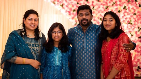 Indian family - father, mother, and two daughters - posing for a photo in cultural dress