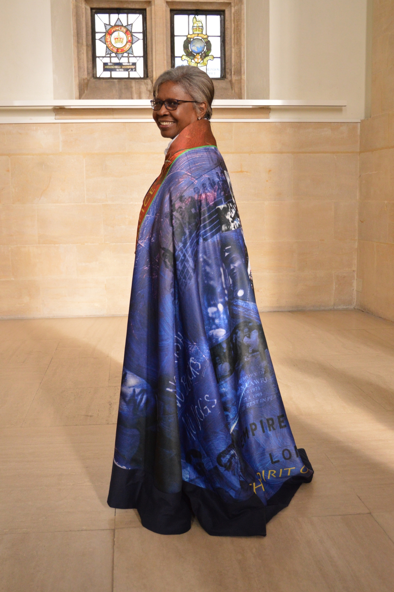 Rev Bev wearing the Windrush Cope with her back angled towards the camera and looking over her shoulder