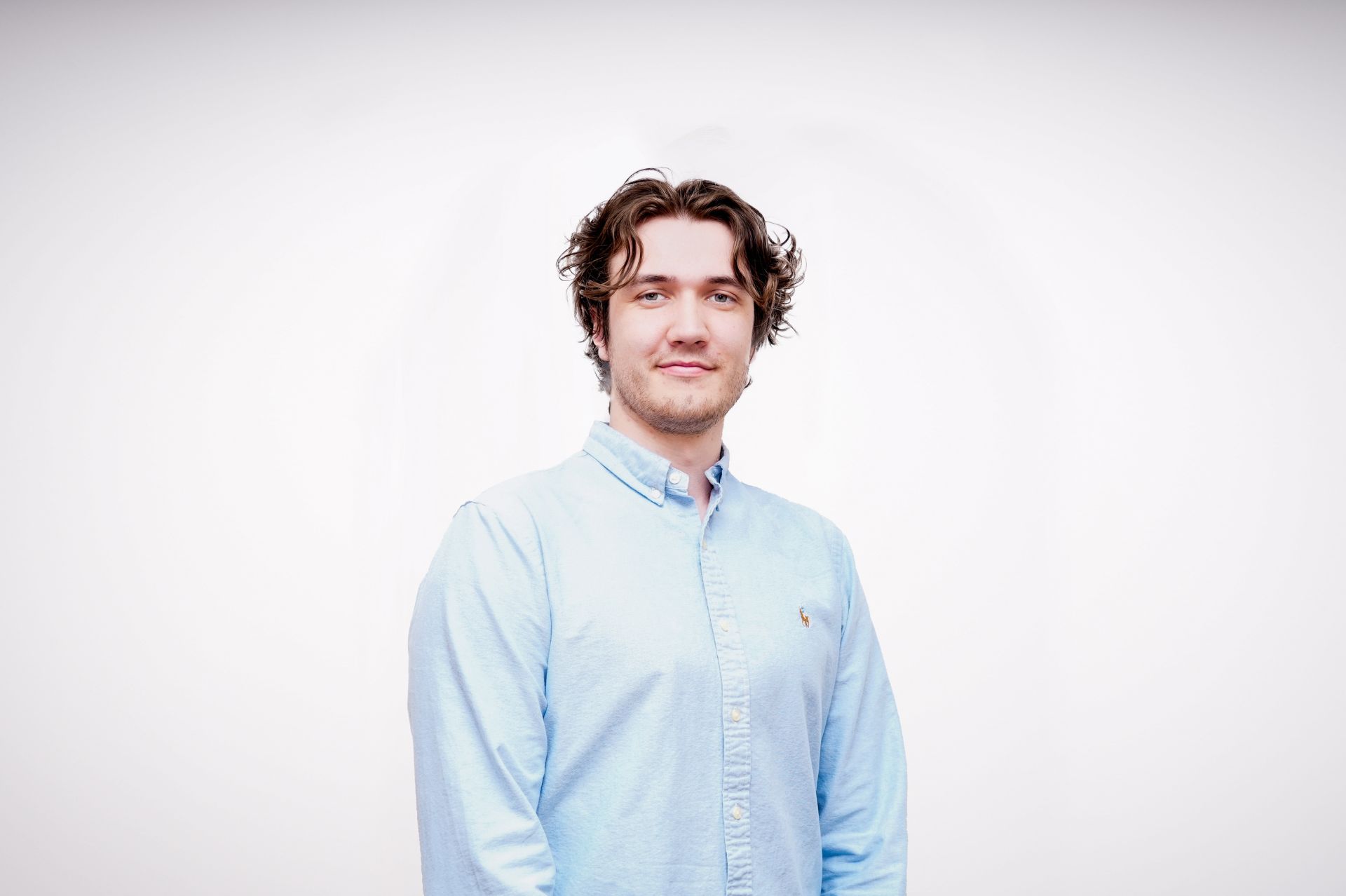 Oliver Phillips wearing blue shirt next to a plain backdrop