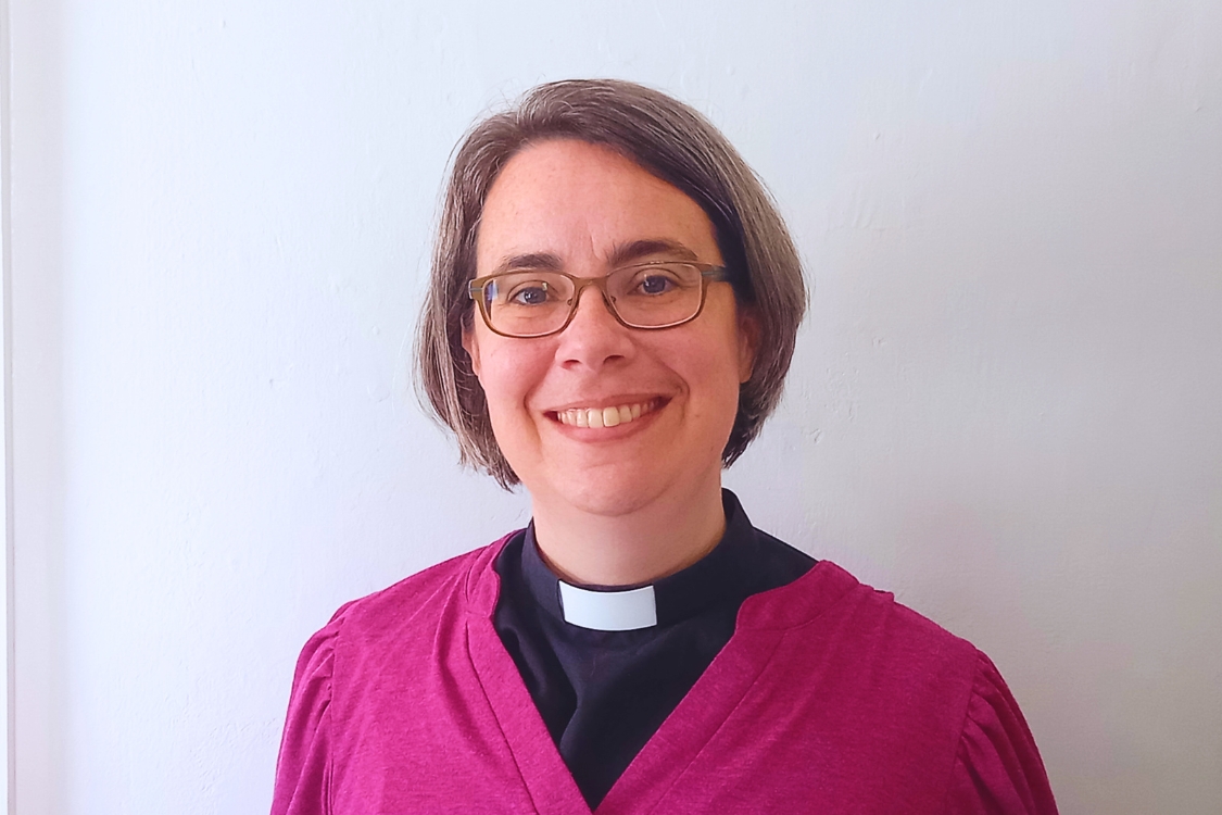 Jenn Riddlestone wearing a purple cardigan and black clerical shirt