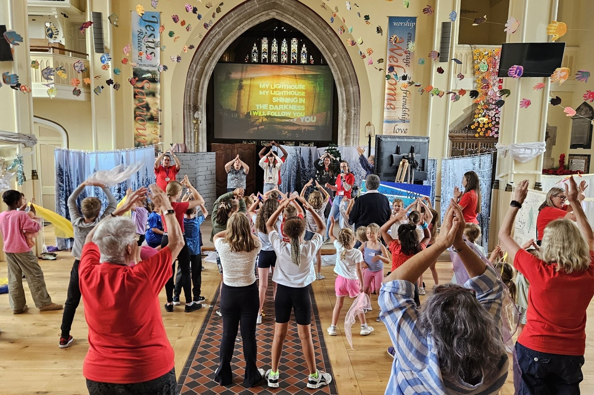 Children and adult volunteers join in with an action song in St Peter's Church in Chertsey
