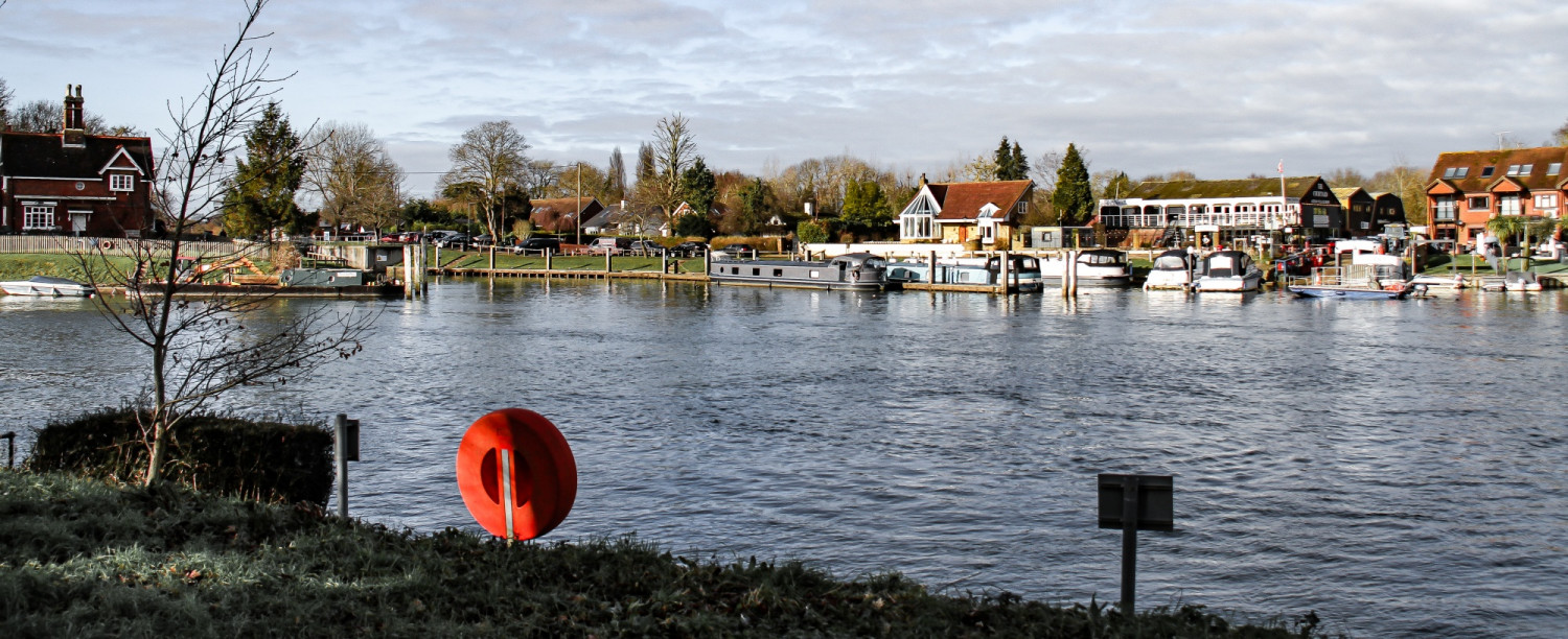 Calm River Thames with boats moored on a cloudy day