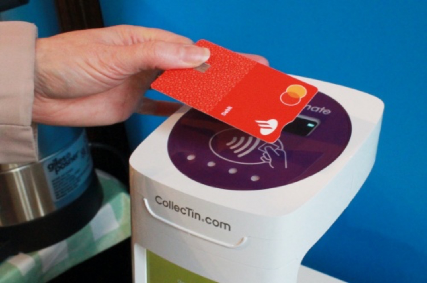Somone tapping a bank card on a contactless payment system