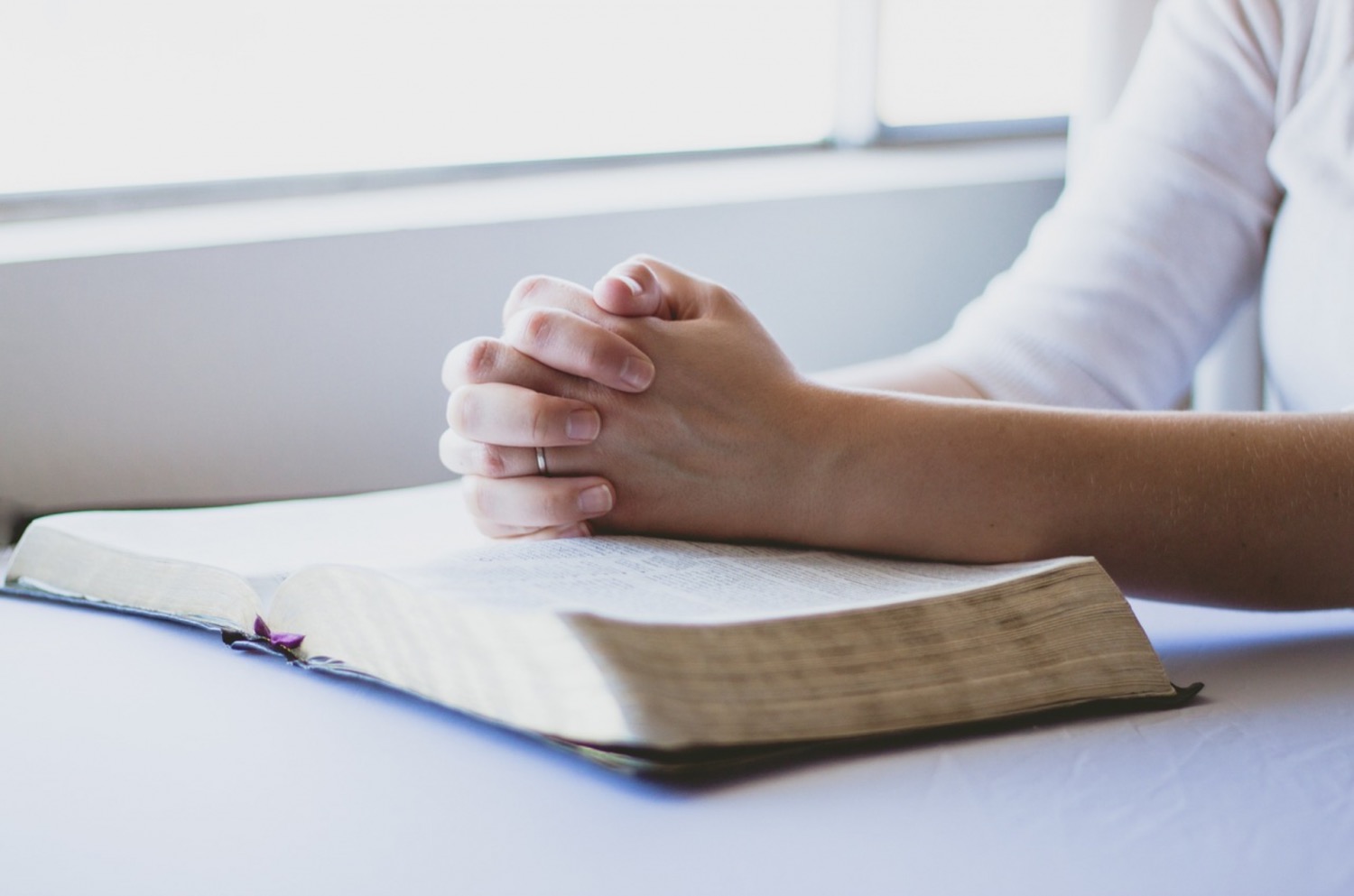 Woman praying, with her hands rested on the Bible
