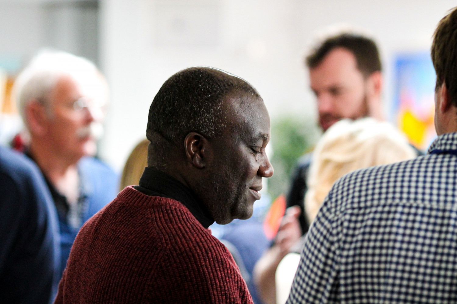 A group of churchgoers in the background and a smiling man in the foreground