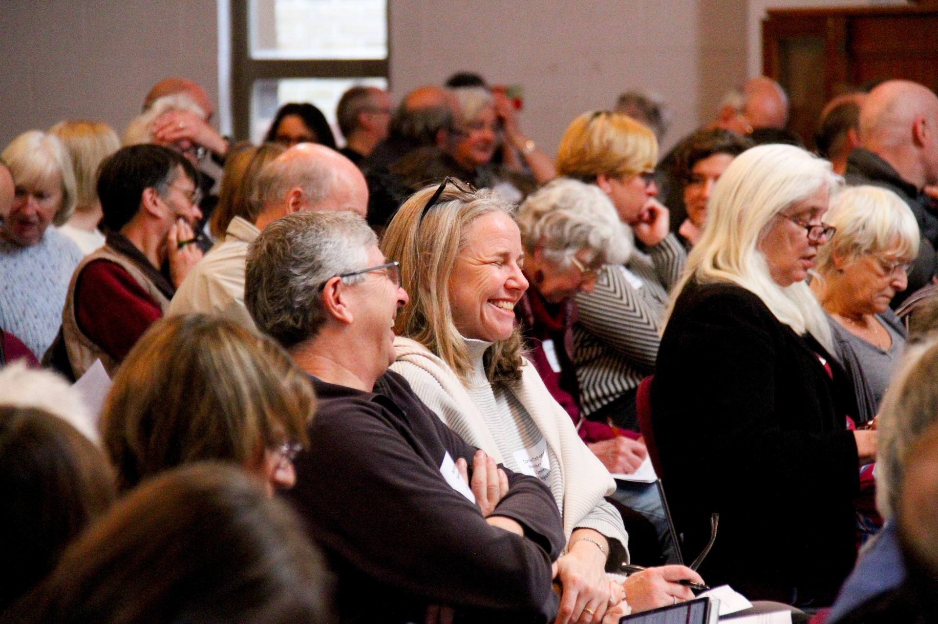 Group of people gathered sat down in conversation, smiling and laughing