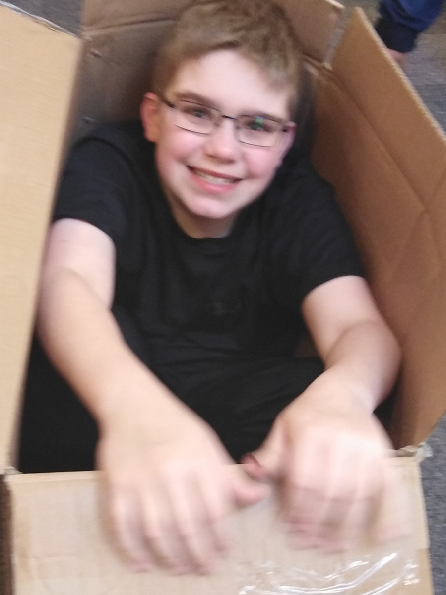 Boy with glasses smiling sat in box