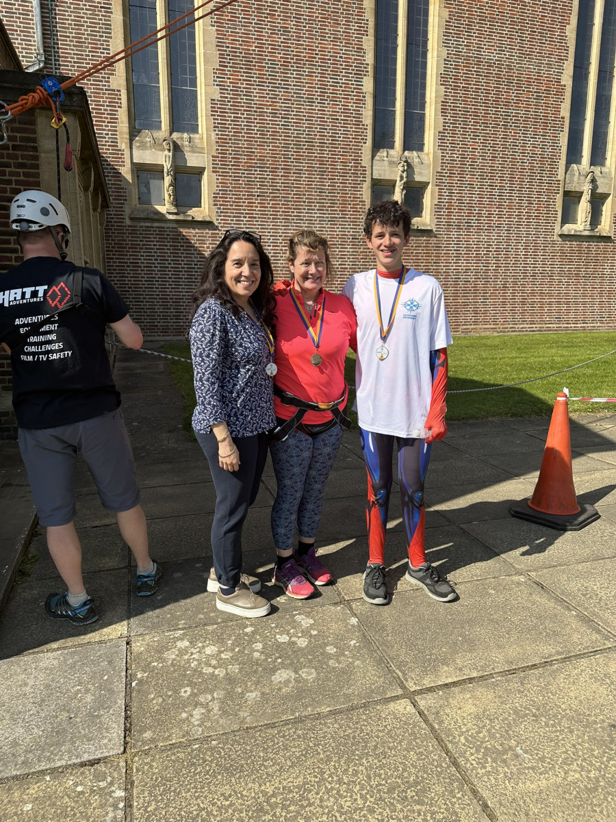 Group of three people (two women and an older boy) wearing matching medals having completed the abseil