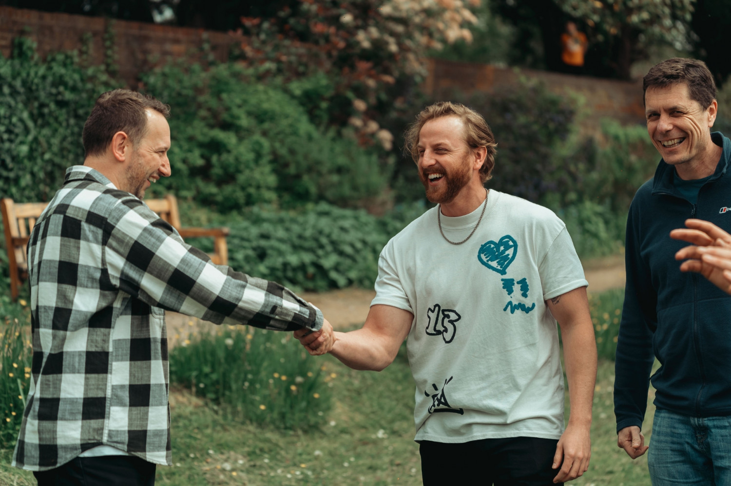 Three men smiling and greeting one another