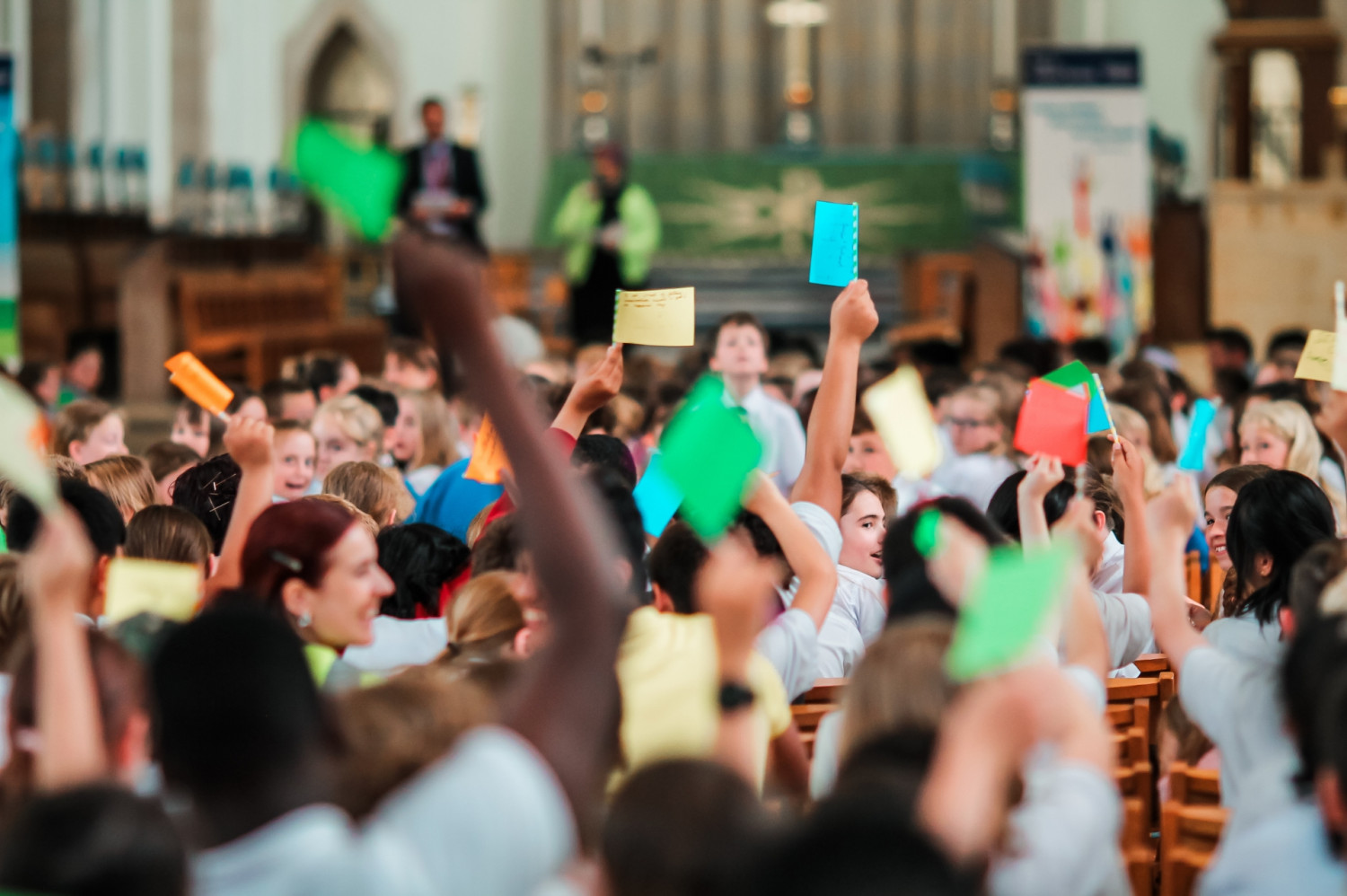 School children waving coloured paper flags in a cathedral